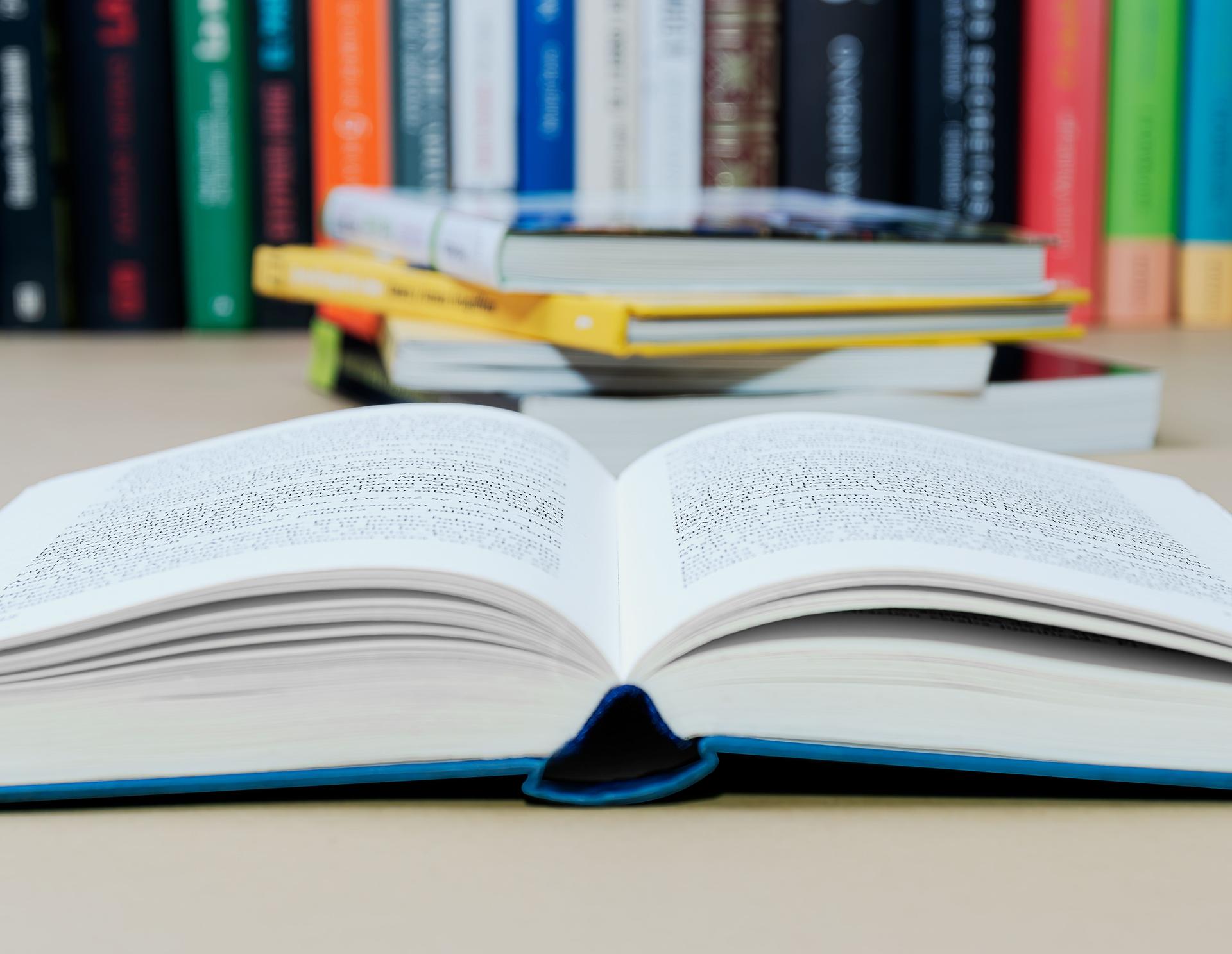 Open book with some blur on a counter and several out focus books in the background.