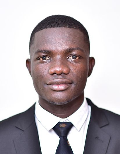 Portrait of a person in a suit and tie, smiling against a plain background.