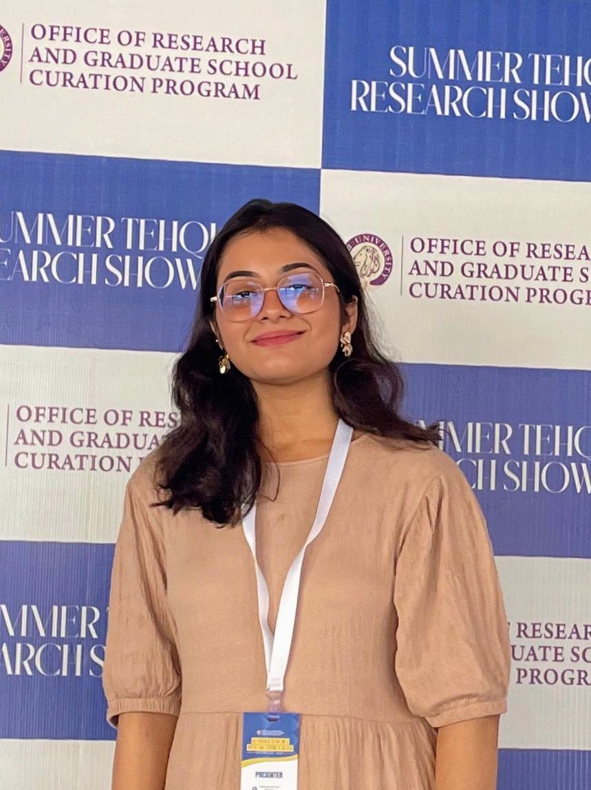 Person standing in front of a backdrop with text related to a research and graduate school program.