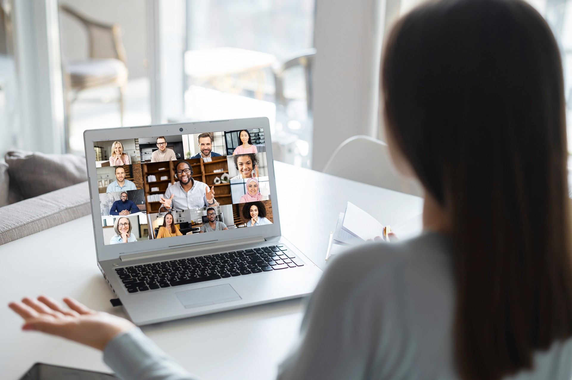 Woman using laptop for video conference, back view