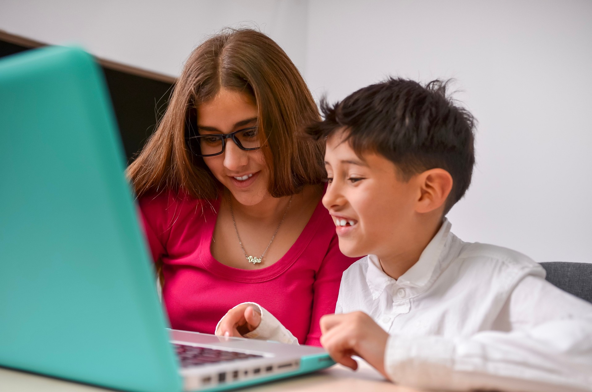 Teenage girl helping a child with his homework on a laptop