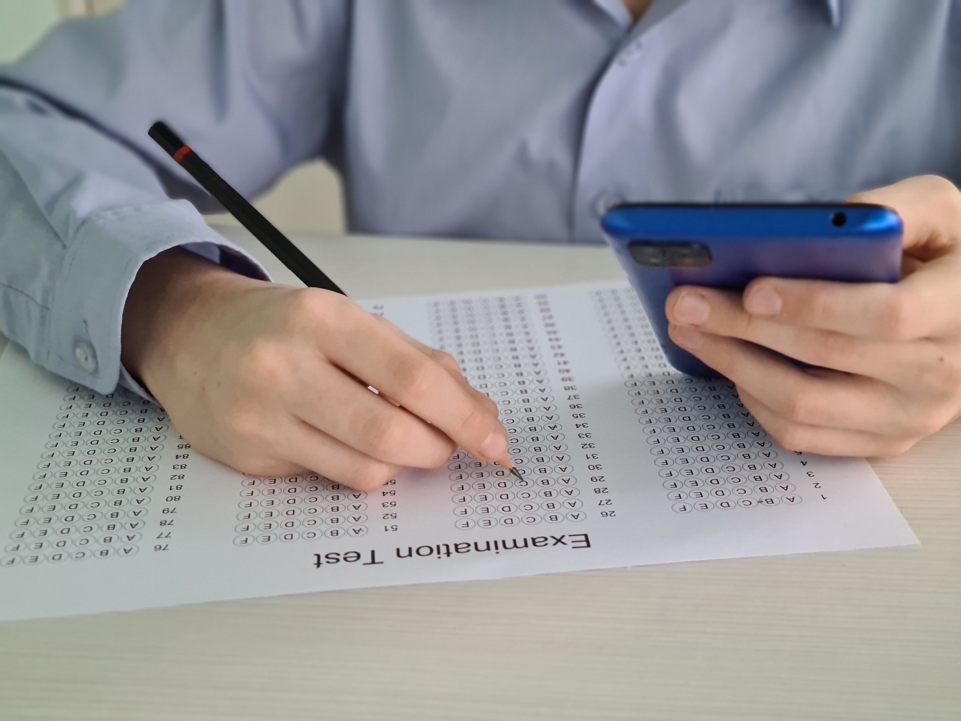 Person Taking Multiple Choice Examination With Smartphone
